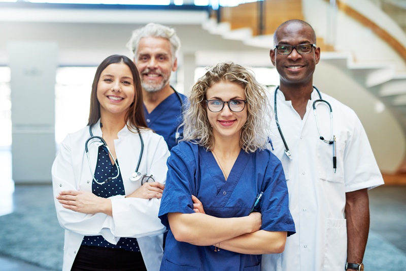 Smiling medical allied health team with arms crossed standing in a clinic and looking at camera.